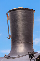 View of the smokestack of an old steam locomotive close-up. Vertical pipe on top of the smokebox that ejects the steam