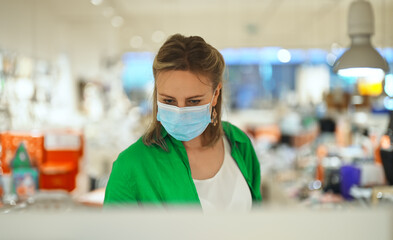 Woman in medical mask chooses a gift in toy store.