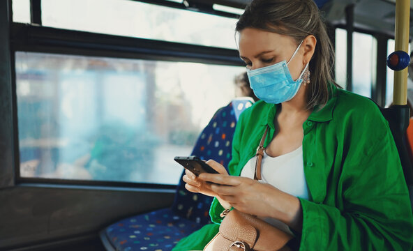 Woman in medical mask with mobile phone in the bus.