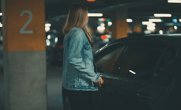 Woman unlocking her car with key in underground parking.