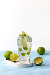 One glass with cold mojito with ice, lime and mint. Fresh Lemonade, tonic on blue background.