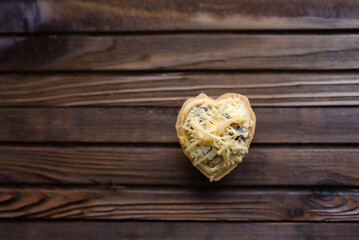 Fototapeta na wymiar heart shaped cheese tart on wooden background
