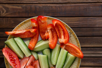 Cut vegetables - tomato, pepper, cucumber on a wooden board