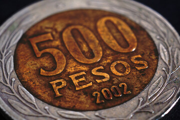 Translation: 500 pesos. Coin of 500 Chilean pesos close-up. Peso of Chile. News about economy or banking. Loan and credit. Money and taxes. Macro