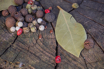Bay leaves with the background of a walnut trunk along with pepper and allspice