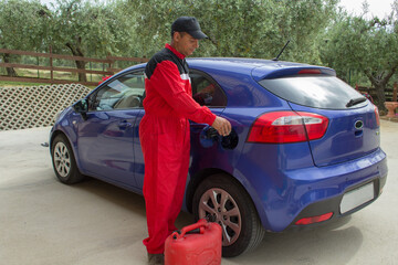 Image of a mechanic in overalls as he pours an additive into the tank of a car. Reference to...