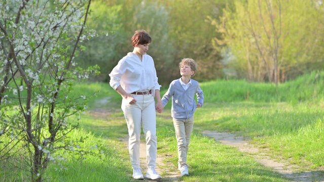Happy family. Loving tender mum walks with a cute son in a spring park. Mommy and Kid outdoor together.