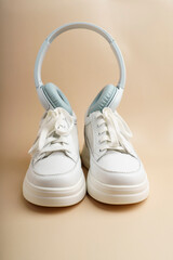 White wireless headphones and white sneakers on a beige background