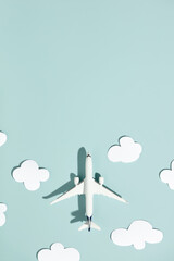 Miniature toy airplane and paper clouds on colorful background. Flat lay design of travel concept