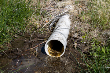 White PVC irrigation pipe feeding water stream from underground source in Wyoming
