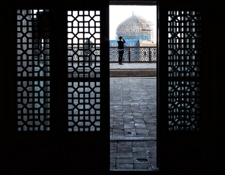 Rear view of a man taking a photo of a mosque from Naqsh-e Jahan Square, Isfahan, Iran