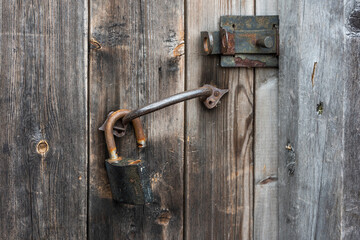 old rusty metal padlock on an old wooden door