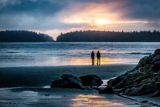 Silhouette of two people standing on beach at sunset, Tofino, Vancouver Island, British Columbia, Canada