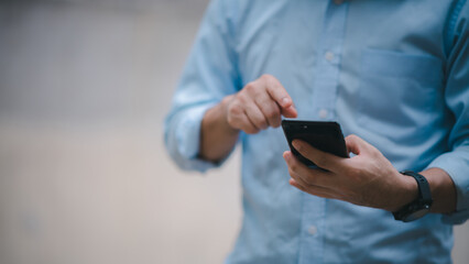 Close up on casual Man using smart phone, using mobile smart phone and online working on laptop computer at home office.