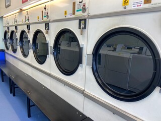 Row of industrial laundry machines in laundromat in a public laundromat, in uk