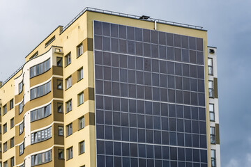 solar panels on the wall of a multi-storey building on storm clouds background. Renewable solar energy. an energy-efficient home that uses the energy of the earth, sun, air and wastewater