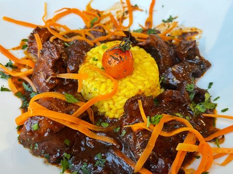 Close-up of octopus stew with saffron risotto and carrot garnish