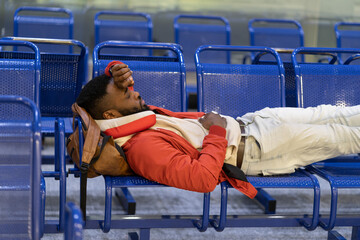 Young African American man is napping while waiting for flight. Closeup of black guy lying on...