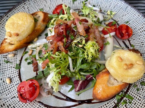 Close-up of a goats cheese salad with lardons and pine nuts