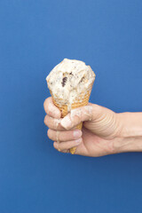 Man's hand holds vanilla ice cream that melts on a dark blue background. Summer sweets melting concept.