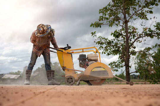 Construction worker using road cutting machinery to cut road surface, Thailand