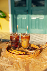 Ice tea and coffee on wooden table outdoors with garden backgound in sunny afternoon