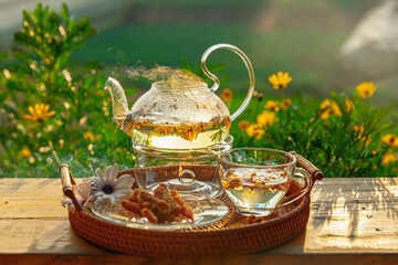 Chrysanthemum tea with hot steam and sweet potato jam on wooden table, in the backyard background...
