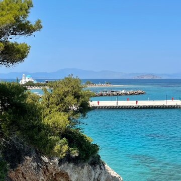 Coastal seascape view with The church of Agioi Anargyroi in distance, Skala, Agistri, Attica, Greece