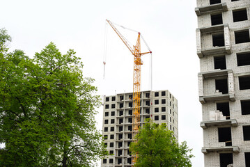 Obraz na płótnie Canvas Construction of a residential building. Tower cranes building a new residential building. Unfinished panel house and construction crane