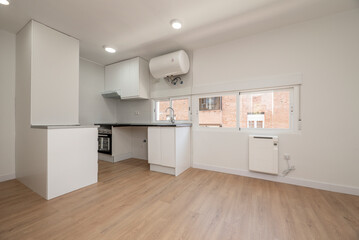 Newly fitted kitchen with shiny black worktop awaiting the washing machine and dishwasher, with electric hot water heater and several windows with views
