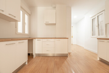 Fototapeta na wymiar Newly installed kitchen cabinets with white cabinets, wooden countertops and matching flooring