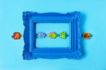 Exotic fishes aligned in an antique blue frame against blue background. Surreal creative concept...