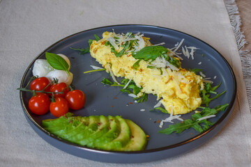 French omelette dish. Delicous homemade french omlette filled with cheese. Plating with fresh vegetables like avocado, cherry tomatoes, but also basil and mozzarella.