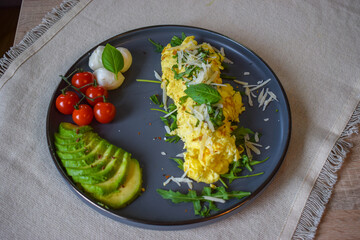 French omelette dish. Delicous homemade french omlette filled with cheese. Plating with fresh vegetables like avocado, cherry tomatoes, but also basil and mozzarella.