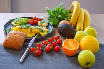French omelette dish. Delicous homemade french omlette filled with cheese. Plating with fresh vegetables like avocado, cherry tomatoes, but also basil and mozzarella.