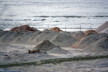 Zwały piasku i kamieni na plaży na budowie przekopu 
