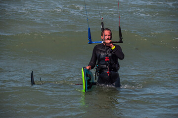 Kite Surfer goes out of the sea with foilboard and trapeze
