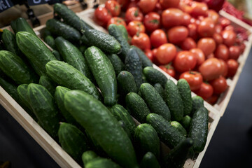 A counter with vegetables in a supermarket. Cucumbers and tomatoes on the counter 