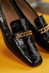 Women's lacquered black loafers close-up on a yellow background. Women's loafers. Style and fashion