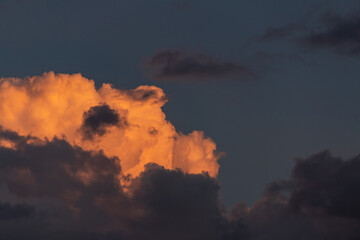 Algumas nuvens fofas e iluminadas pelo sol, no céu escuro do final da tarde.