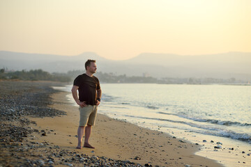 Lonely mature man standing by the sea coast. Single travel. Summer resort vacation.