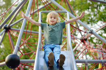 Cute little boy having fun on outdoor playground. Spring summer autumn active sport leisure for...