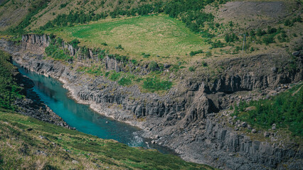 Fototapeta na wymiar Aerial drone panorama of studlagil canyon in Iceland, picturesque valley with basalt columns standing high on a warm summer day. Overview of the basakt tiwers,