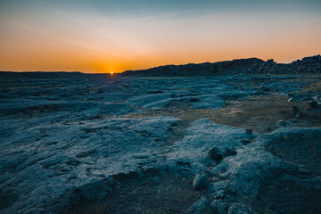 Obraz premium Magnificent rock formations in the Dettifoss area in Iceland during summer sunset, blue rock surrounded by beautiful orange light on the sky with flare from setting sun.