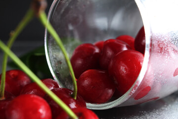 cherry red ripe berry fell out of the glass on a black background with the est for the text....