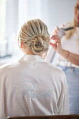 The bride is getting her wedding hair done. Hair stylist makes a hairstyle for a blonde girl. 