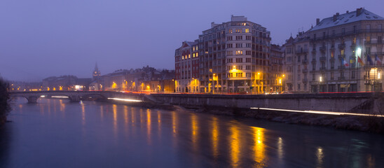 View on the night light of buildings near river in Grenoble of France outdoors.