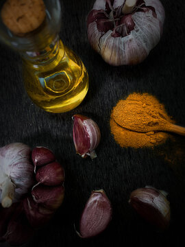 Temperos. Alho, c&uacute;rcuma em colher de pau e azeite de oliva. Dark photography e food style.