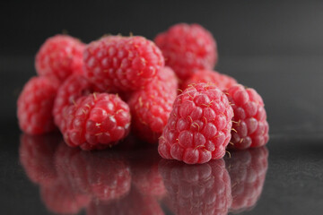 raspberries lie in a heap on a black background with a reflection. Vitamins seasonal berries freshness taste benefit. Raspberries for packaging labels
