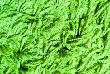Green texture of pile, threads and wool. Close-up macro photo of the carpet